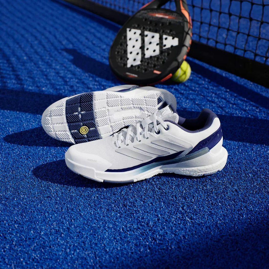 Adidas Crazyquick Boost men's padel shoes (White/Dark Blue) - pair on court, one turned over to show the sole