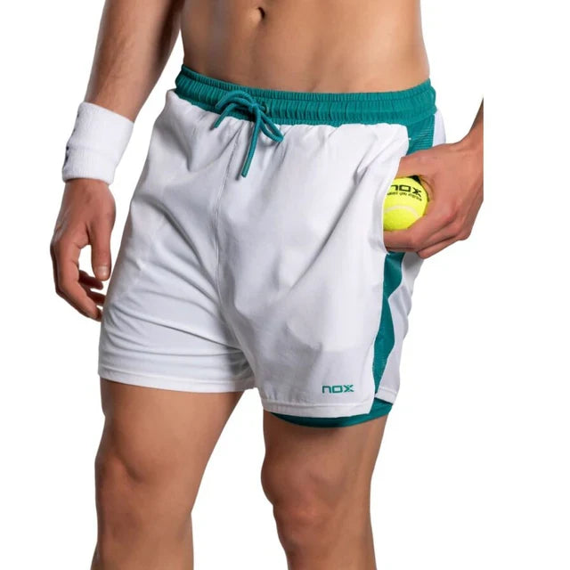 2026 Nox Pro men's padel shorts (White/Ivy Green) - side pocket holding a padel ball