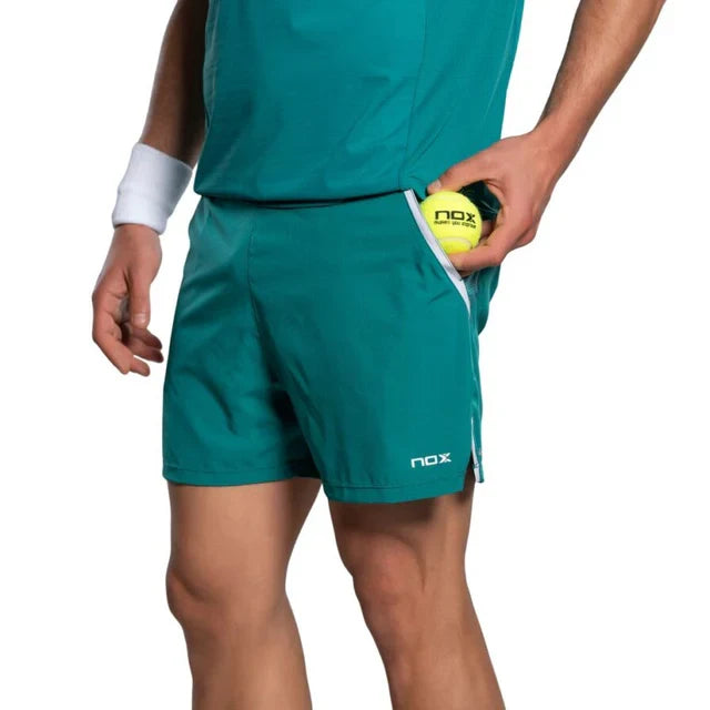 2026 Nox Pro men's padel shorts (Ivy Green) - side pocket holding a padel ball