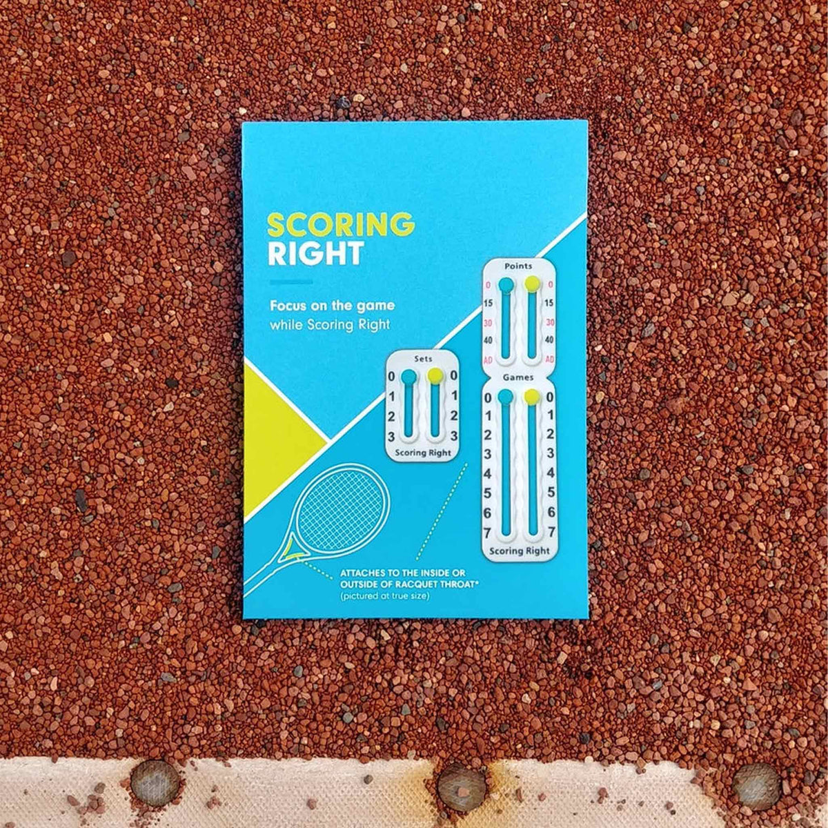 Scoring Right Score Keeper Black - retail pack lying on a red padel court surface